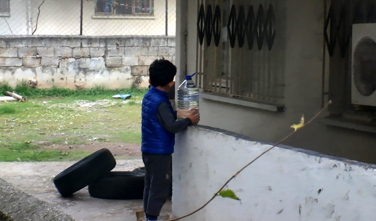 Küçük çocuk yangın söndürme çalışması sırasında bidonla su taşıdı